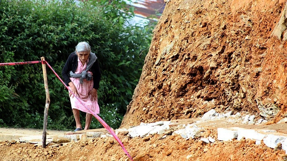 Luis Martínez / Una mujer mayor, atravieza un pequeño sendero que hoy ocupa el lugar de la calle destruída