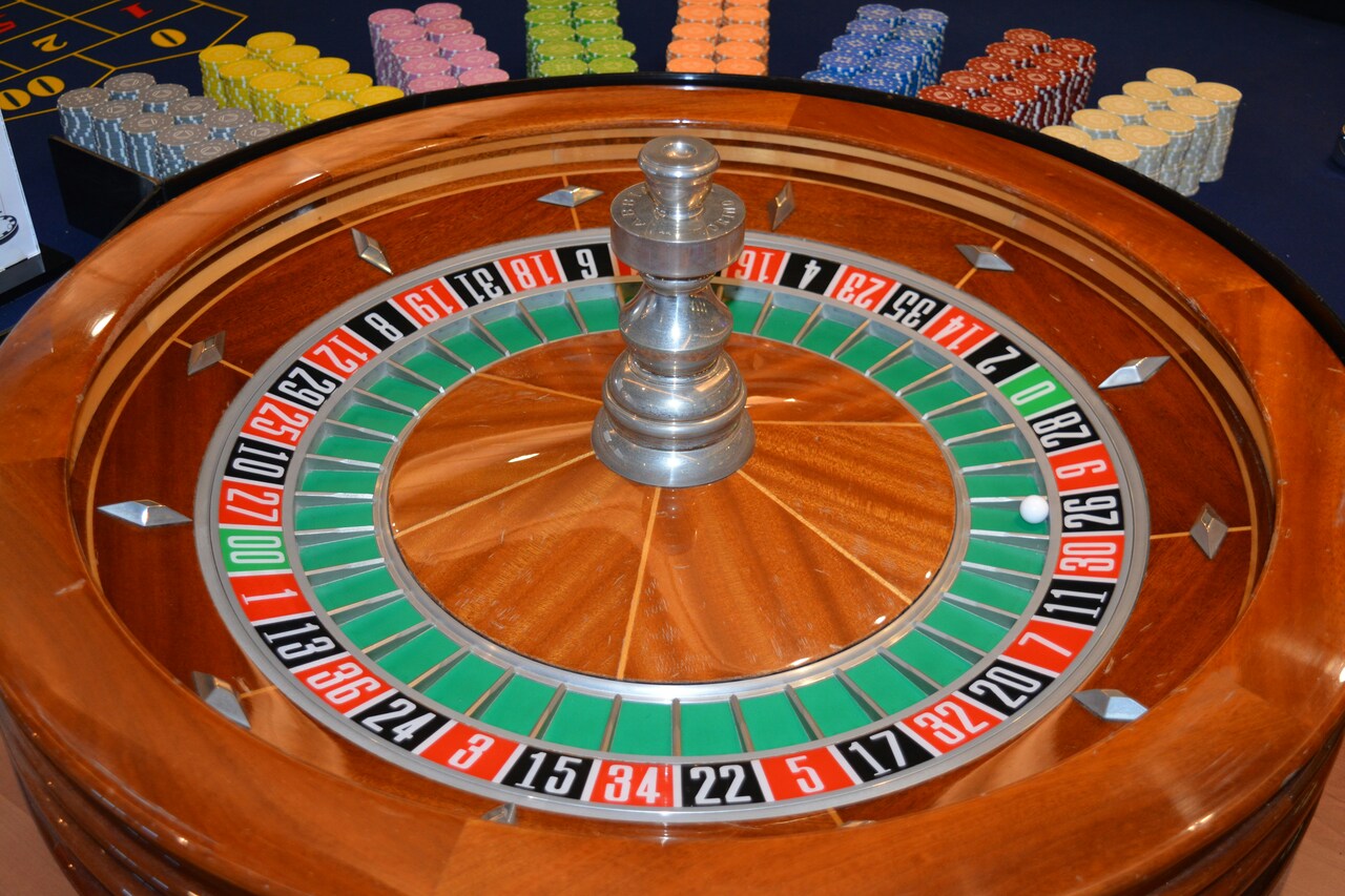 Rueda de ruleta americana en un casino, destacando su diseño clásico con números rojos, negros y verdes, símbolo de azar y entretenimiento