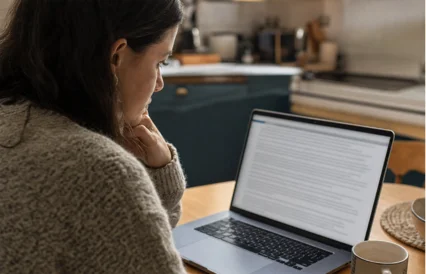 Una mujer revisa con atenci&oacute;n un documento de t&eacute;rminos y condiciones en su laptop